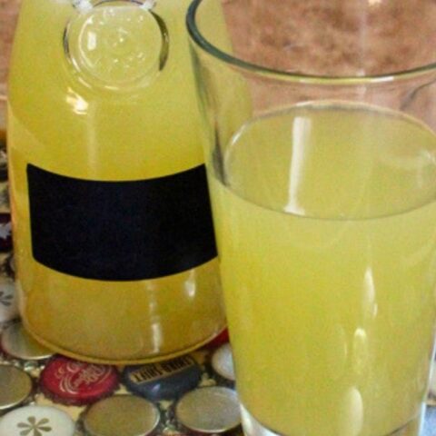 A carafe of Star Trek inspired tranya beside of glass of the pale yellow drink.