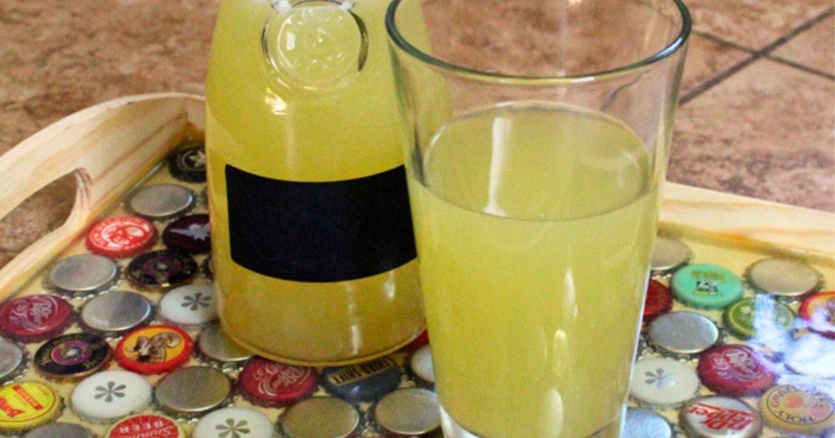 A carafe of Star Trek inspired tranya beside of glass of the pale yellow drink.