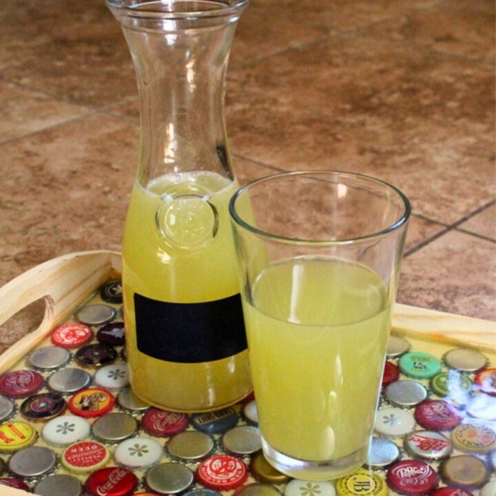 A carafe of Star Trek inspired tranya beside of glass of the pale yellow drink.