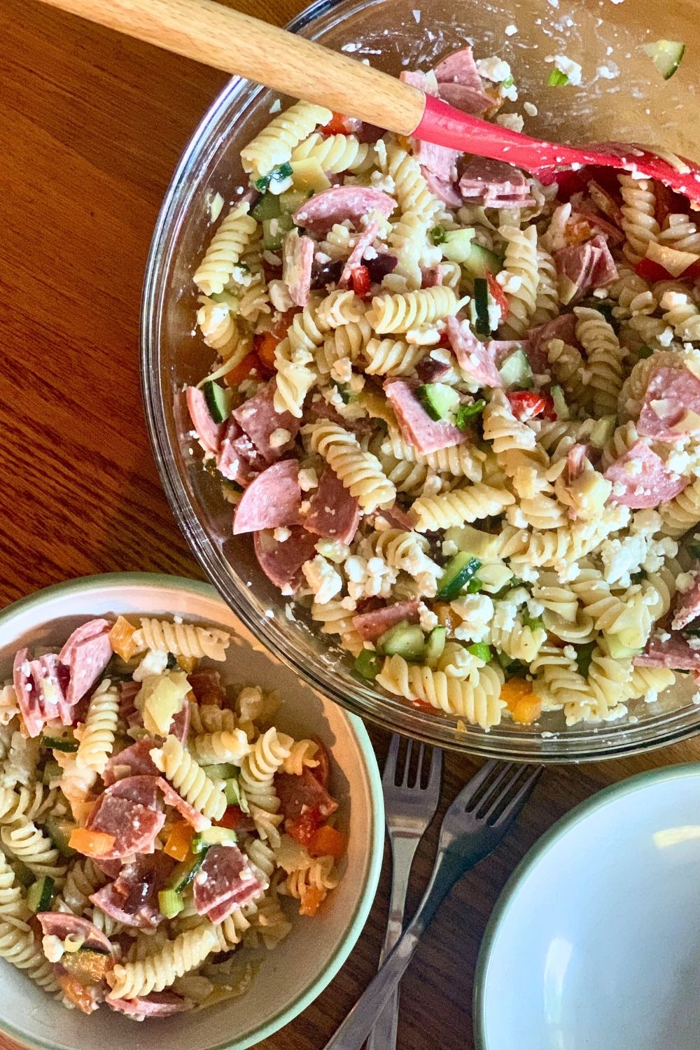 A bowl of Greek pasta salad with rotini, salami, feta, and vegetables.