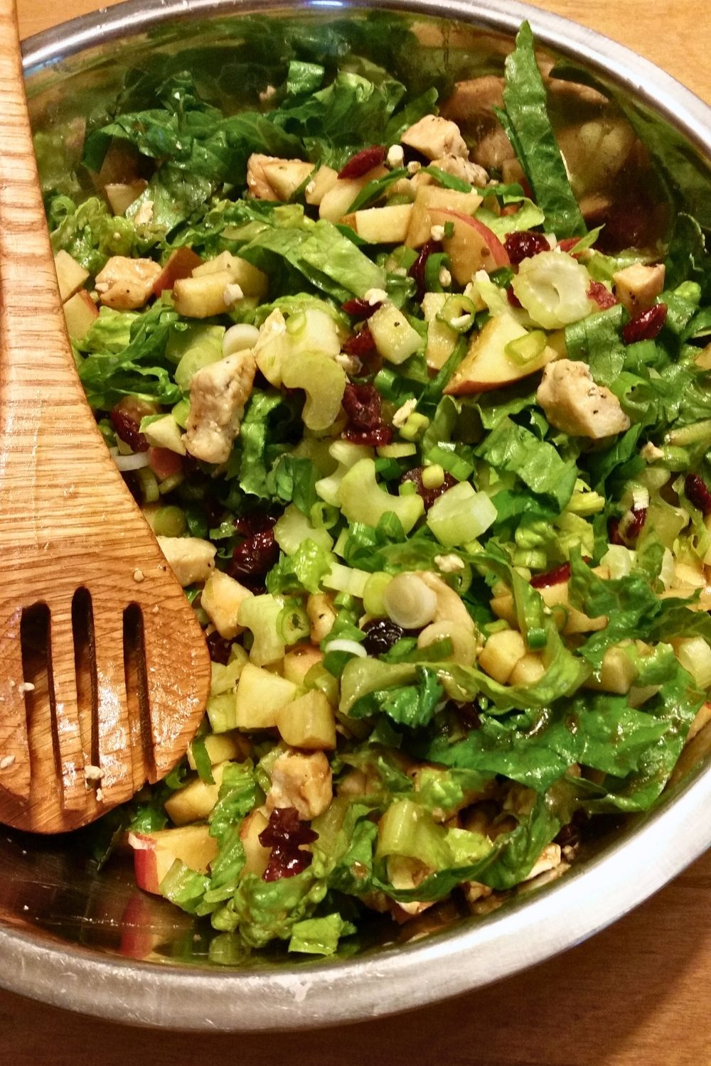 A large bowl with chicken, lettuce, apples, celery, and feta cheese.