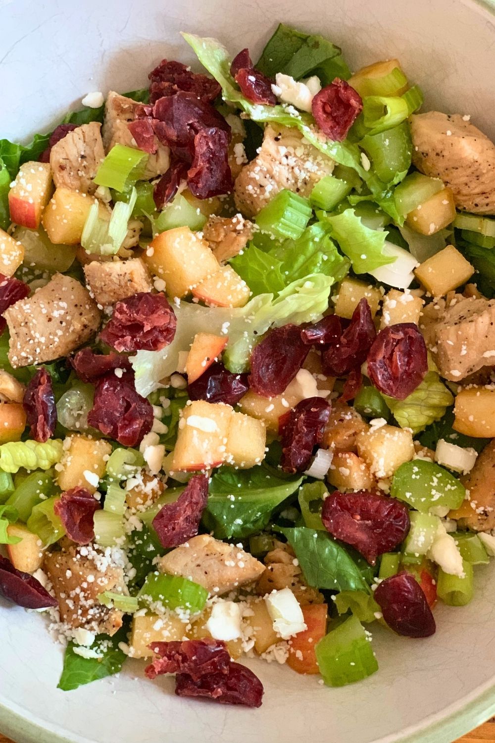 Closeup of salad with lettuce, chicken, dried cranberries, and feta.