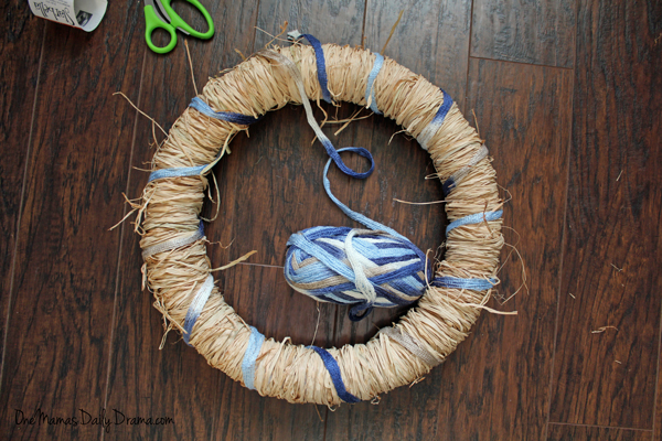 Blue yarn wrapped around the raffia layer of a wreath.