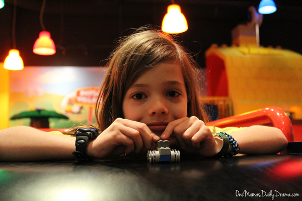child leaning on a table with a LEGO car