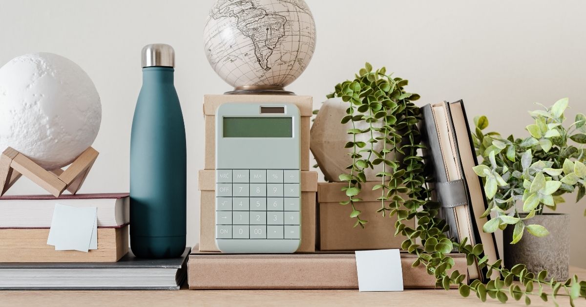 Desk full of school supplies includign books, a water bottle, calculator, and globe.