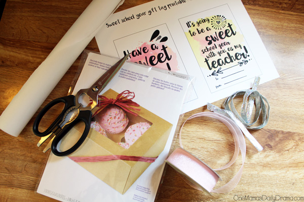 Brown kraft paper box, pink and silver ribbon, parchment paper, and scissors.