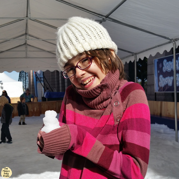 child in a sweater holding a tiny snowman
