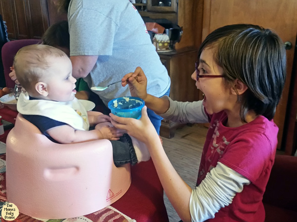 young child feeding a baby a spoonful of cereal