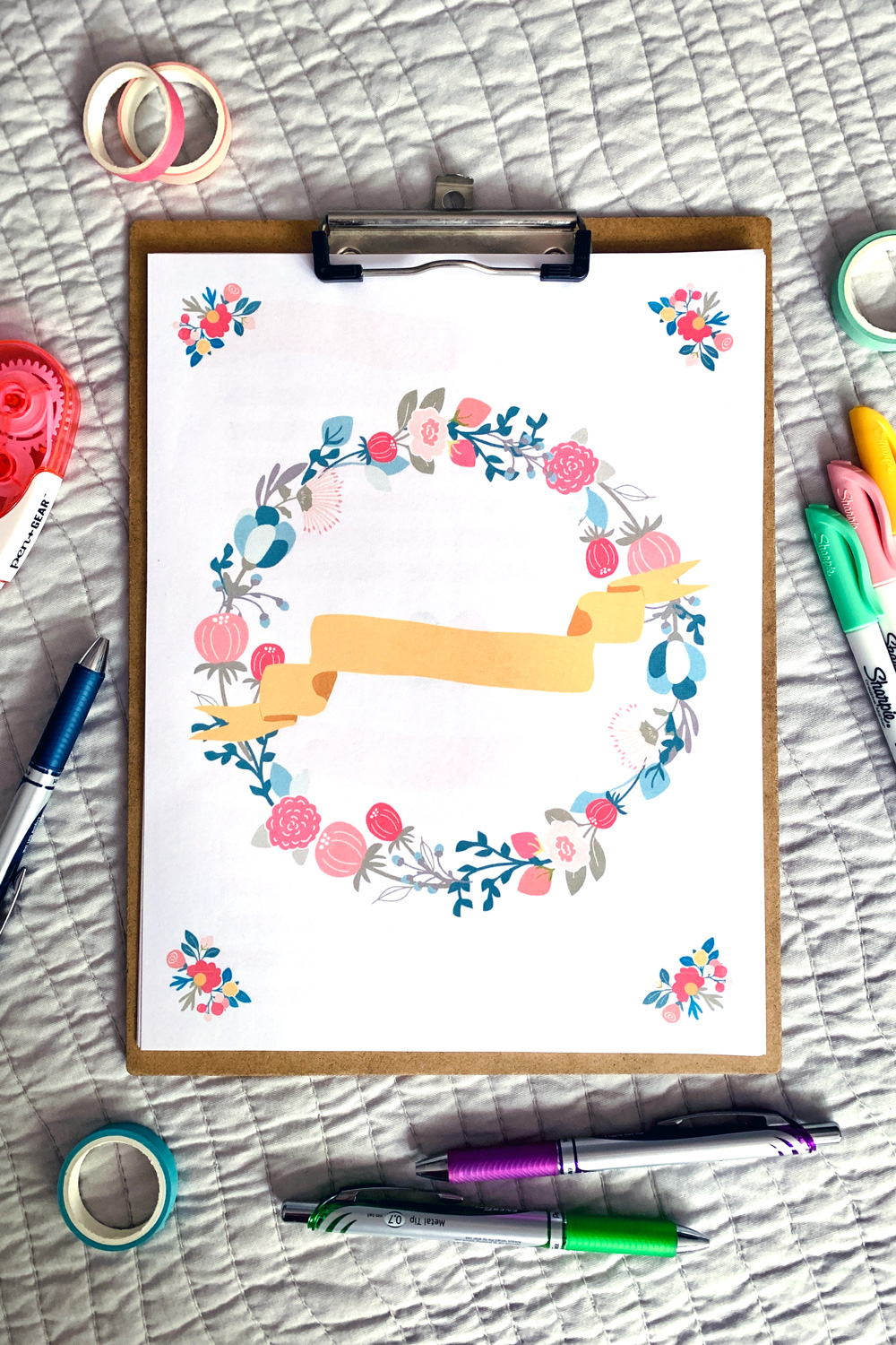 Spring activity book cover with a pink and blue flower wreath and a gold ribbon.