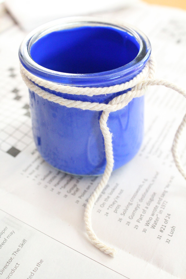 Cotton cord wrapped twice around a blue glass jar and looped.