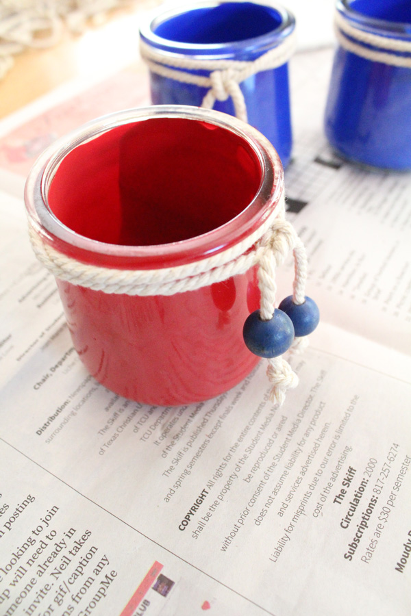 Cotton cord wrapped twice around a red painted jar and tied with blue beads hanging from the ends.