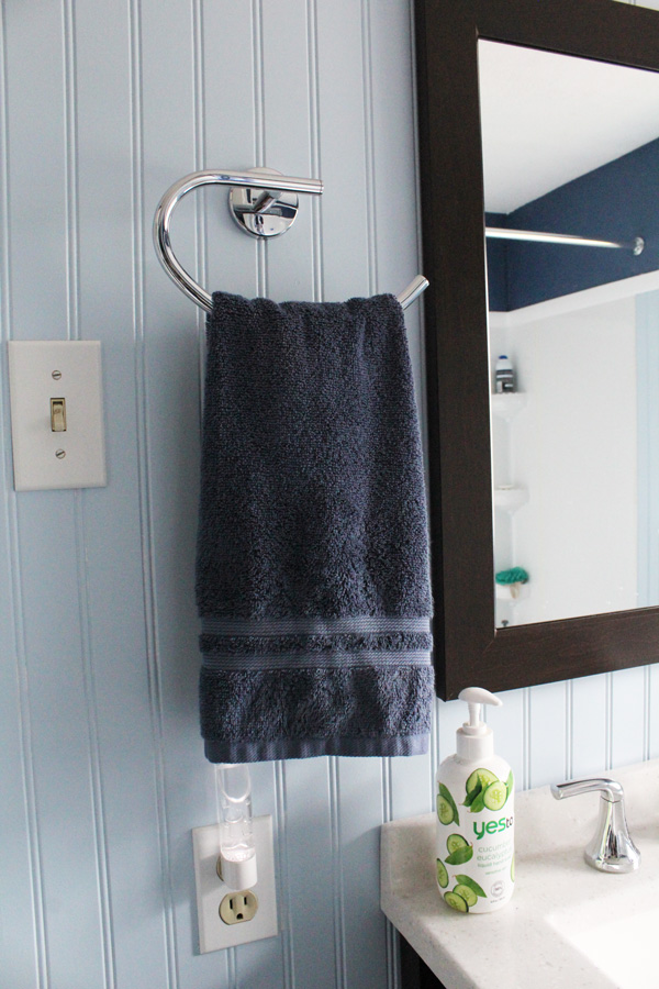 closeup of navy towel, chrome towel ring, and sink