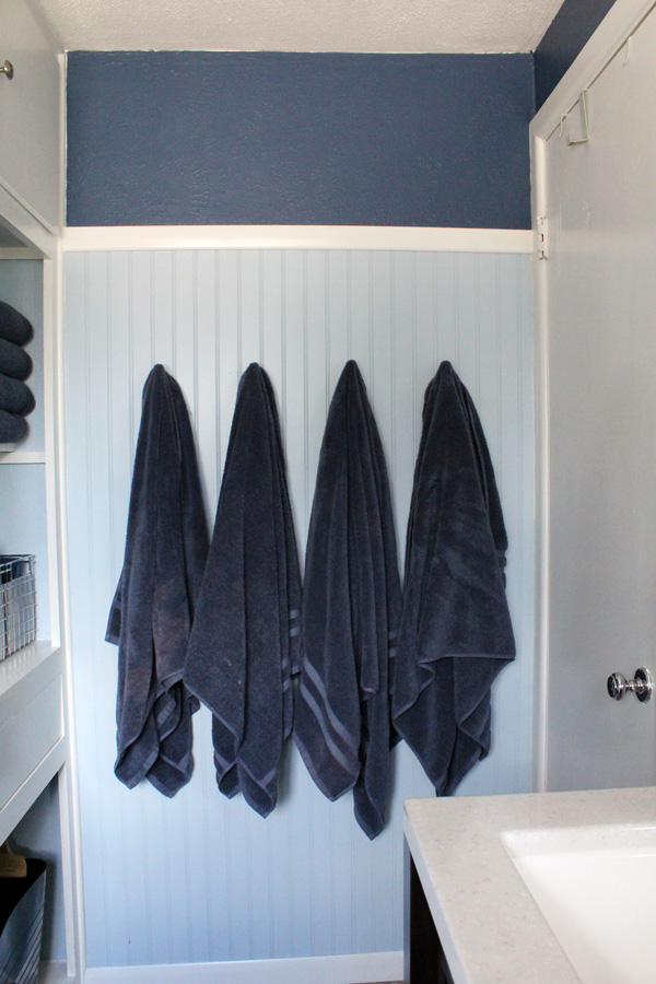 bathroom remodel: navy towels hanging on a light blue and dark blue wall
