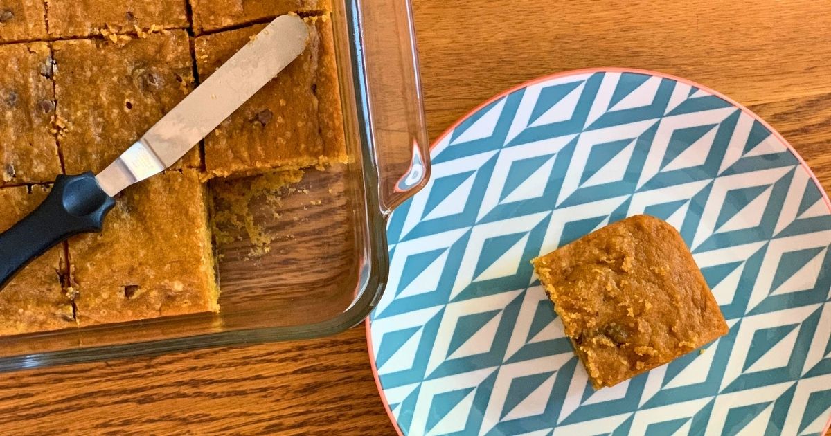 Pumpkin chocolate chip bars in a pan with one slice removed to a plate.