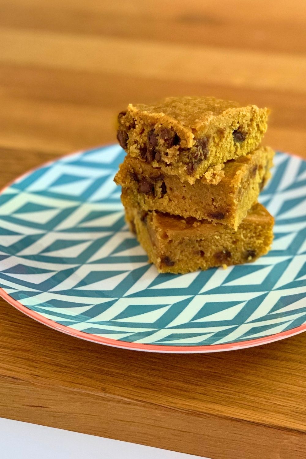 A stack of 3 chocolate chip pumpkin dessert bars on a plate.