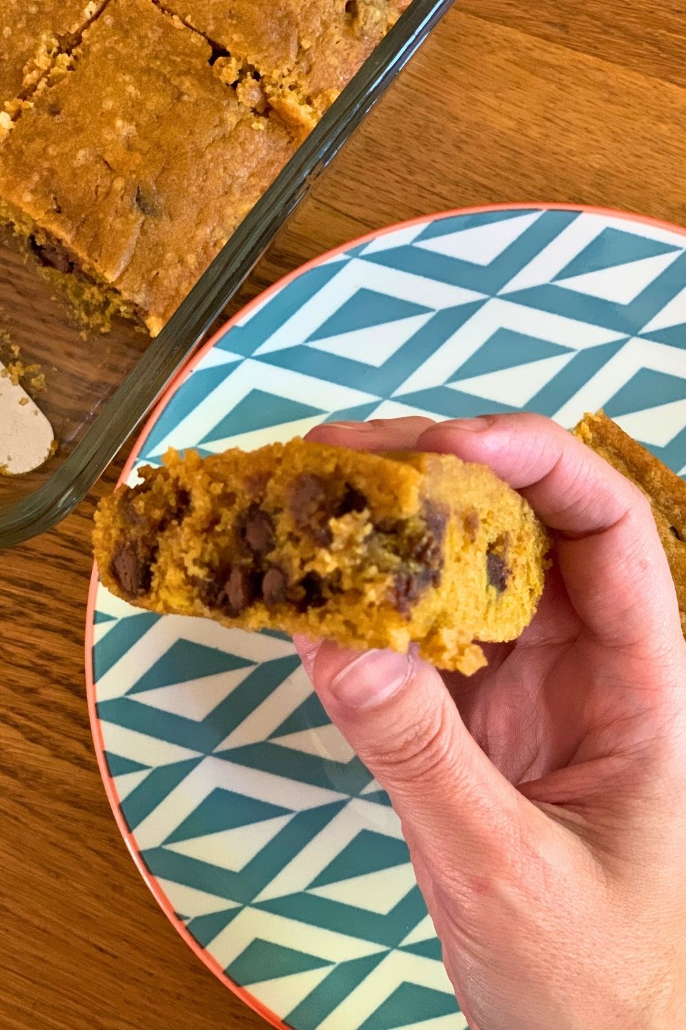 A hand holding a sliced bar to show the side stuffed with chocolate chips.