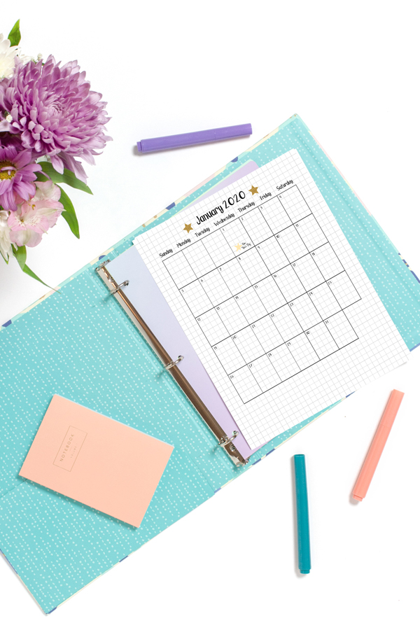 A January bullet journal calendar in a blue binder with New Year's Day marked with a sticker.