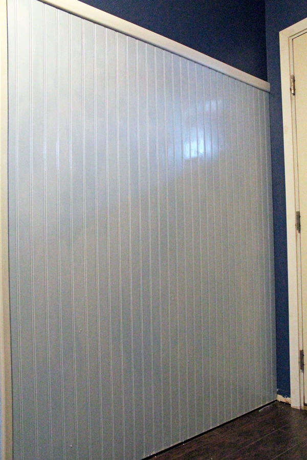 A 6-foot paneled wall with light blue paint, white trim, and dark blue wall above the paneling.