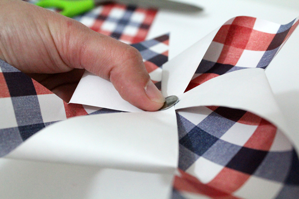 hand pressing a thumbtack into a paper pinwheel craft