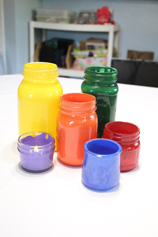 colorful mason jar candle holders on a white tablecloth