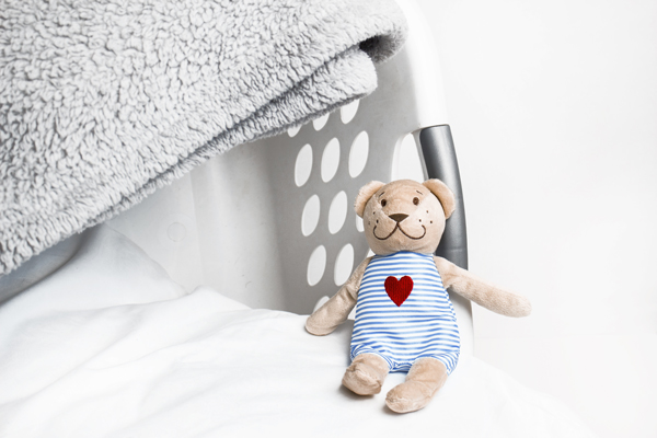 a stuffed bear in a basket of laundry