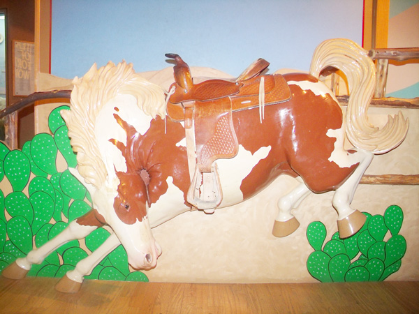 a bucking bronco statue has a saddle and steps for kids to climb up and sit