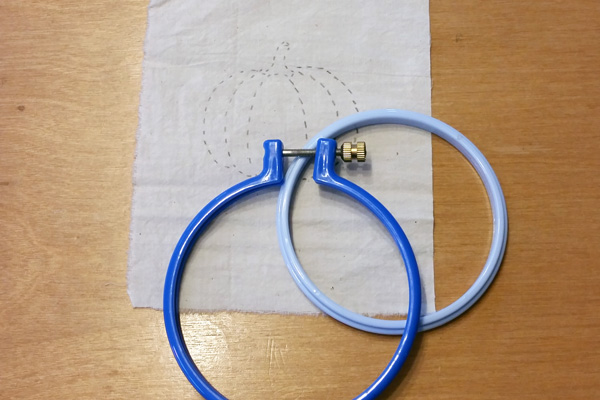 blue embroider hoop in 2 pieces sitting on a fabric pattern