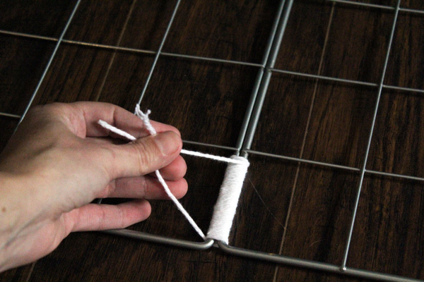 hand tying the ends of a white yarn knot together
