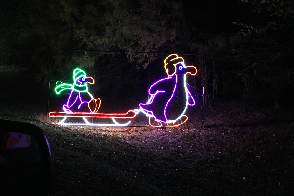 a lighted display showing a penguin pulling another penguin on a sled