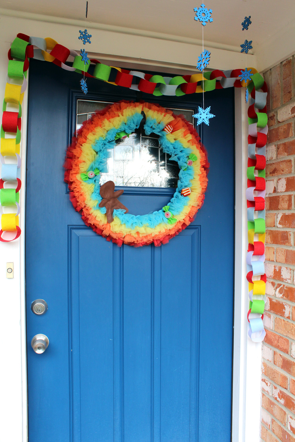 blue door with a rainbow and candy wreath, rainbow garland, and blue snowflakes