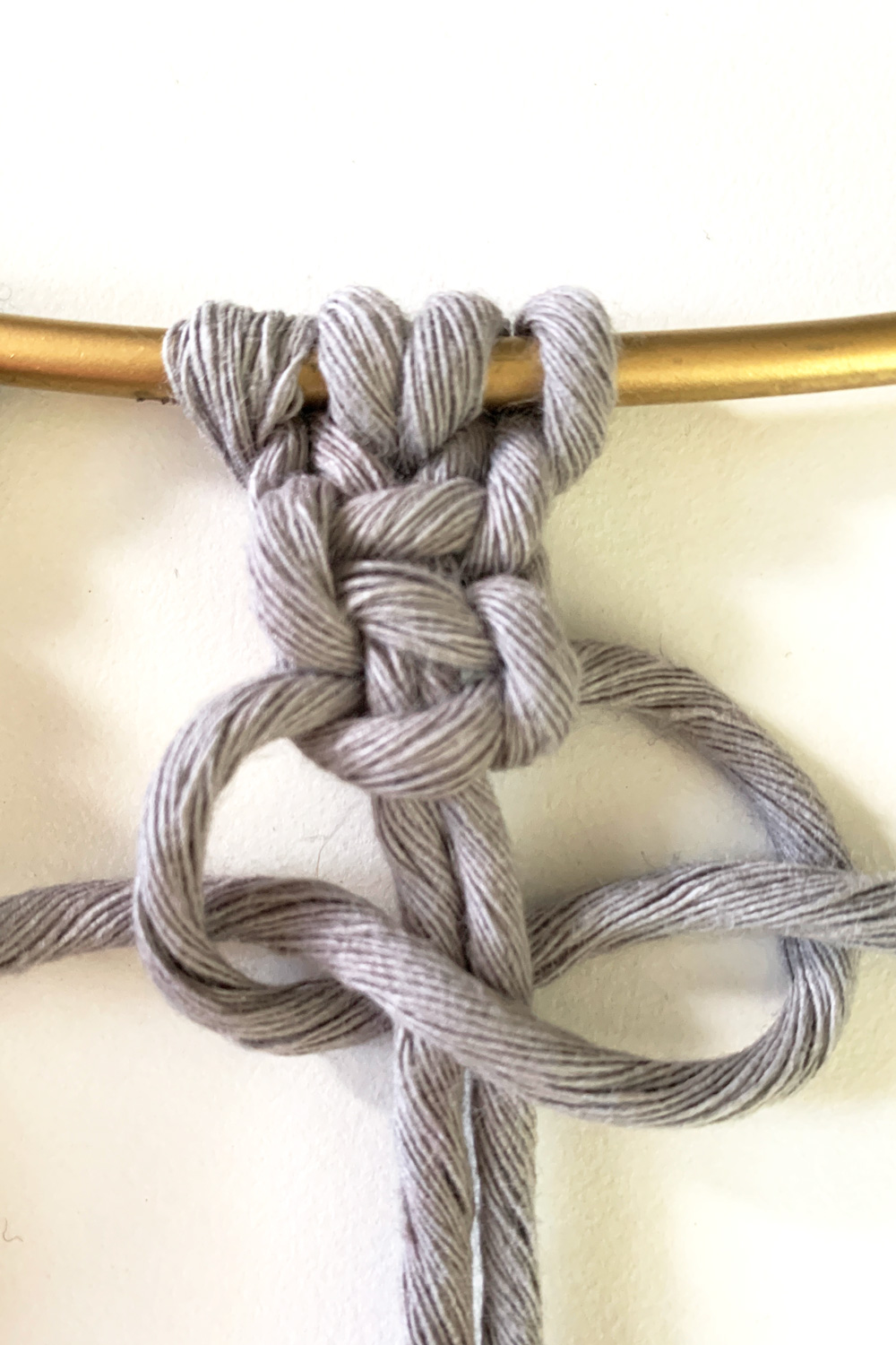 Gray macrame cords tied in the opposite direction to finish the box knot.