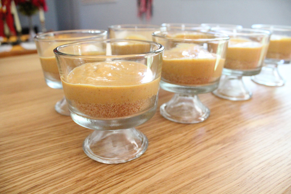 8 parfait glasses filled with graham cracker crust and pumpkin pudding.