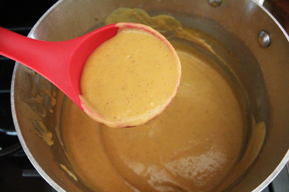 Using a ladle to scoop up pumpkin pudding from a saucepan.