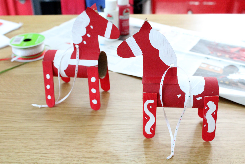 2 paper tube dala horses painted red with white decorations.