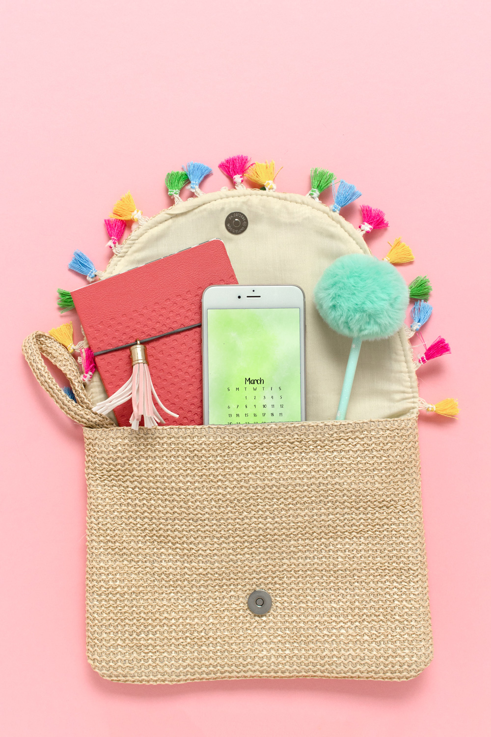 Purse with a phone that has a green watercolor wallpaper featuring a March calendar.