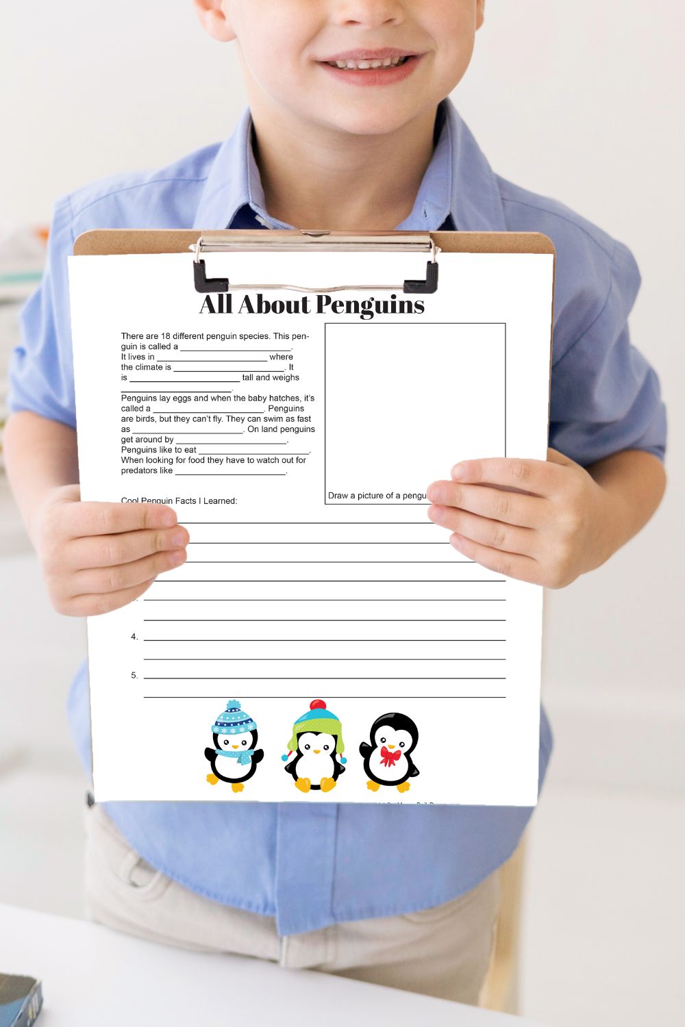 Child holding a penguin facts activity sheet on a clipboard.