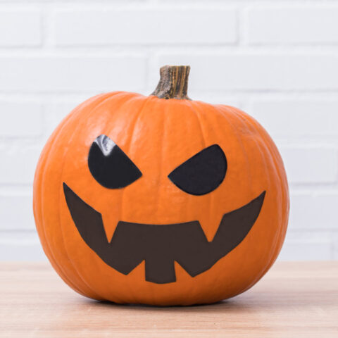Jack o'lantern with black tape pumpkin carving template eyes and toothy mouth.