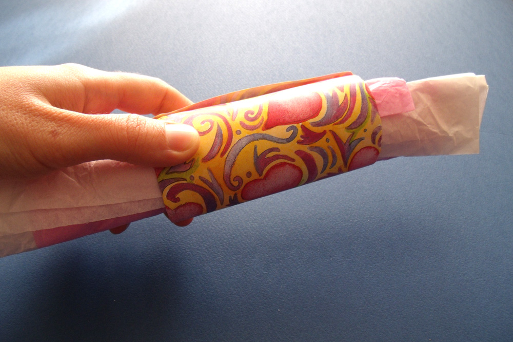 Sliding a tissue paper roll into a paper tube.