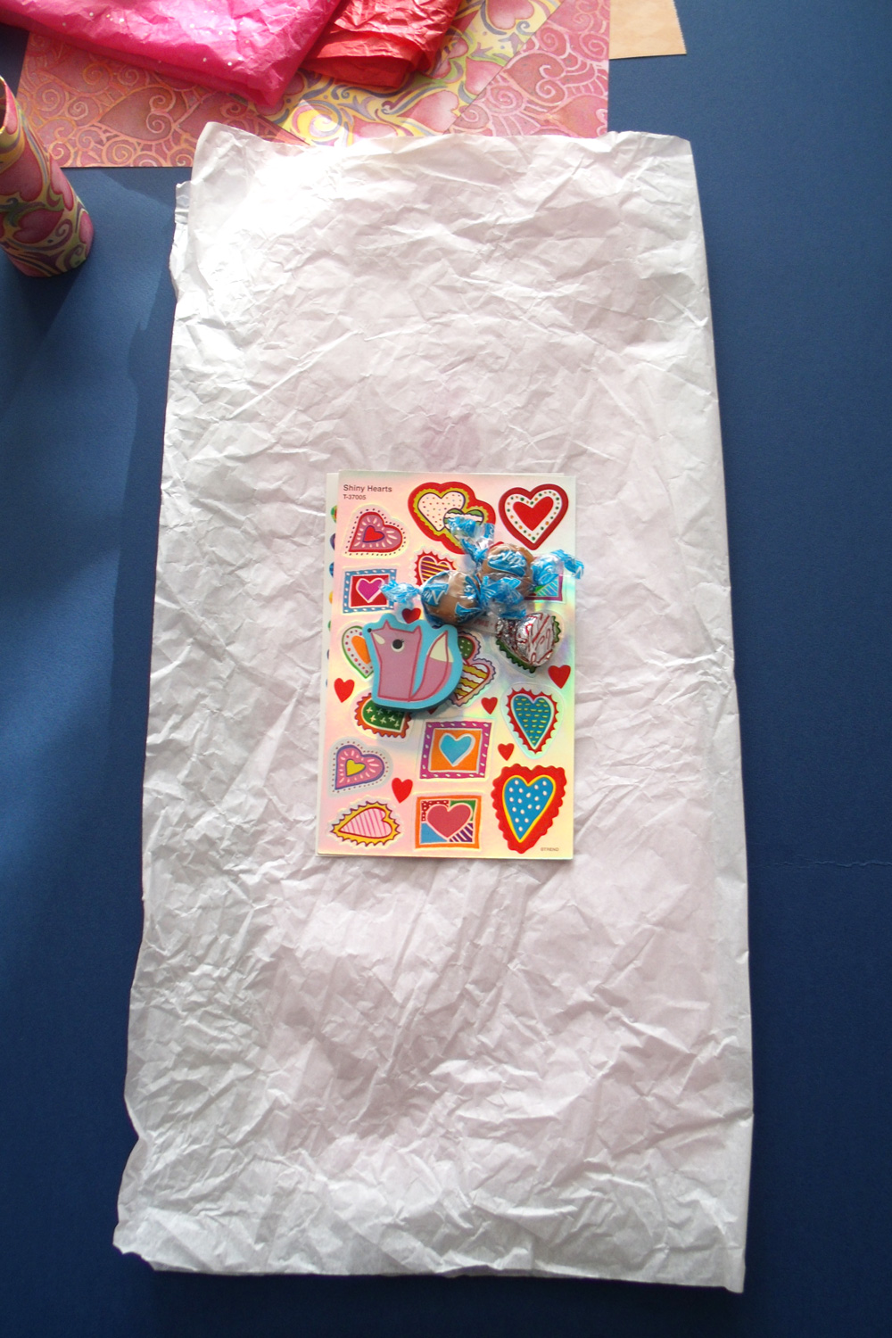Sheets of stickers, candy, and a fox eraser centered on a stack of tissue paper.