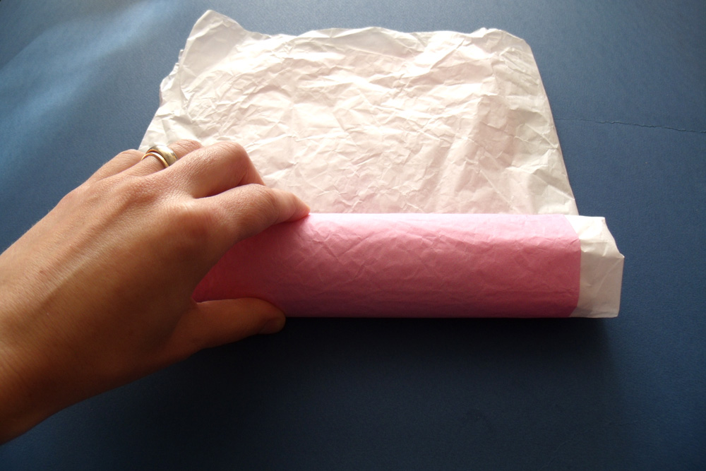 Rolling tissue paper around treats into a tube shape.