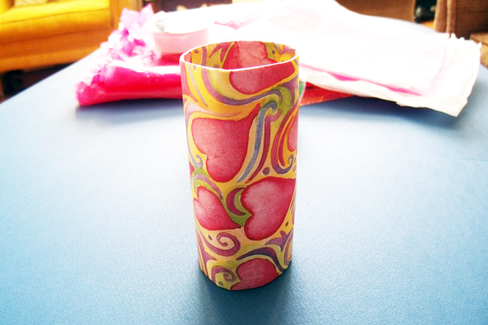 A paper tube covered with pink heart-patterned paper.
