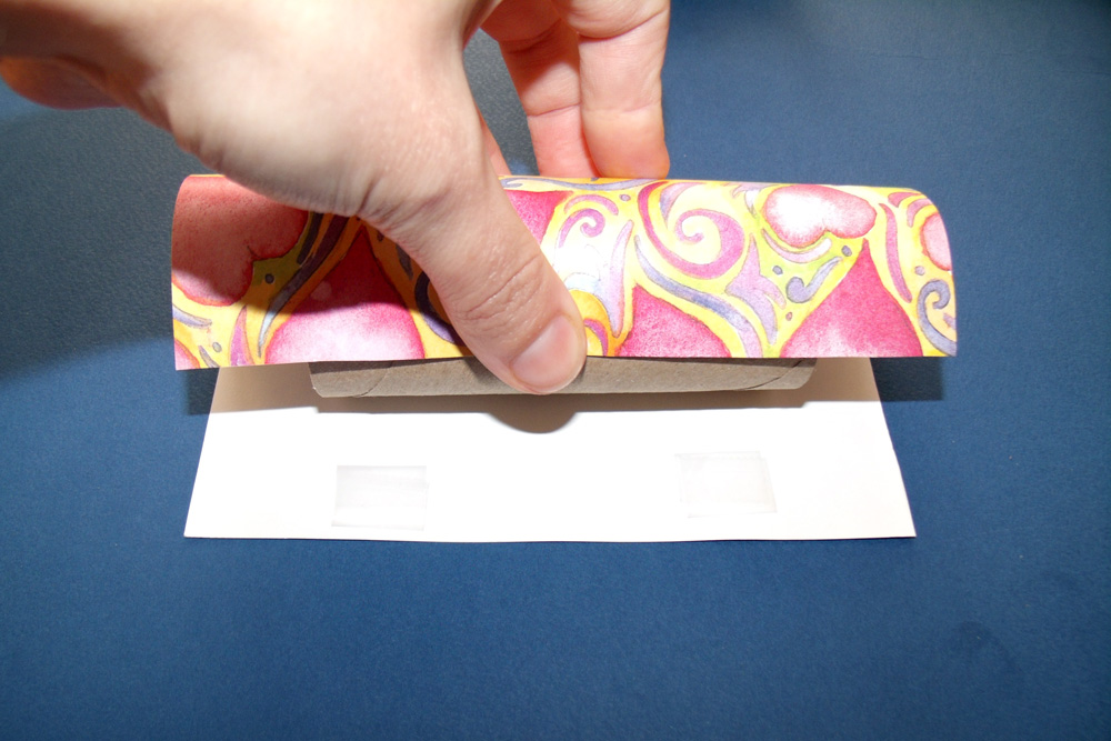 Wrapping scrapbook paper around a toilet paper tube.