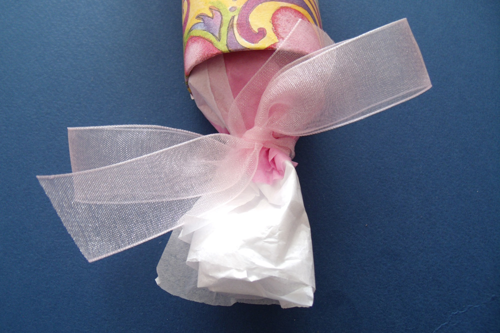 A pink ribbon tied around the end of a tissue paper tube.