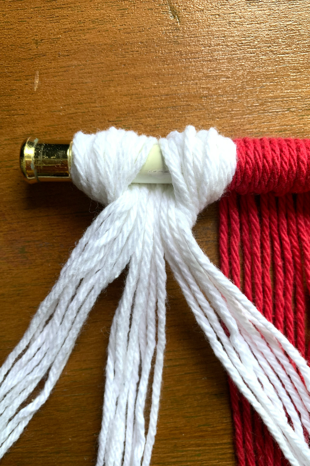 White yarn in a hitch knot separated into three groups.
