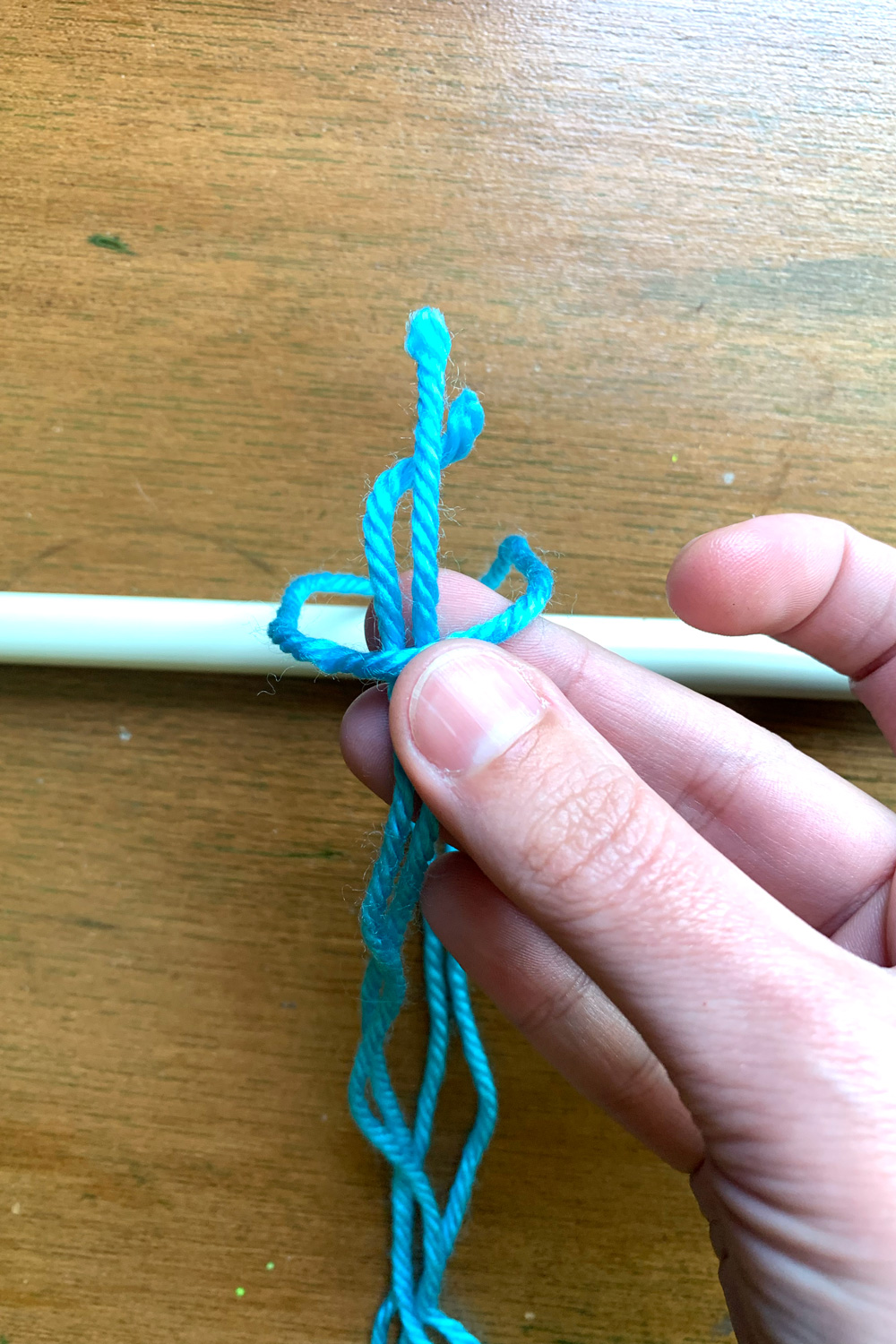 Looping the cut ends of yarn through the other end around the metal rod.
