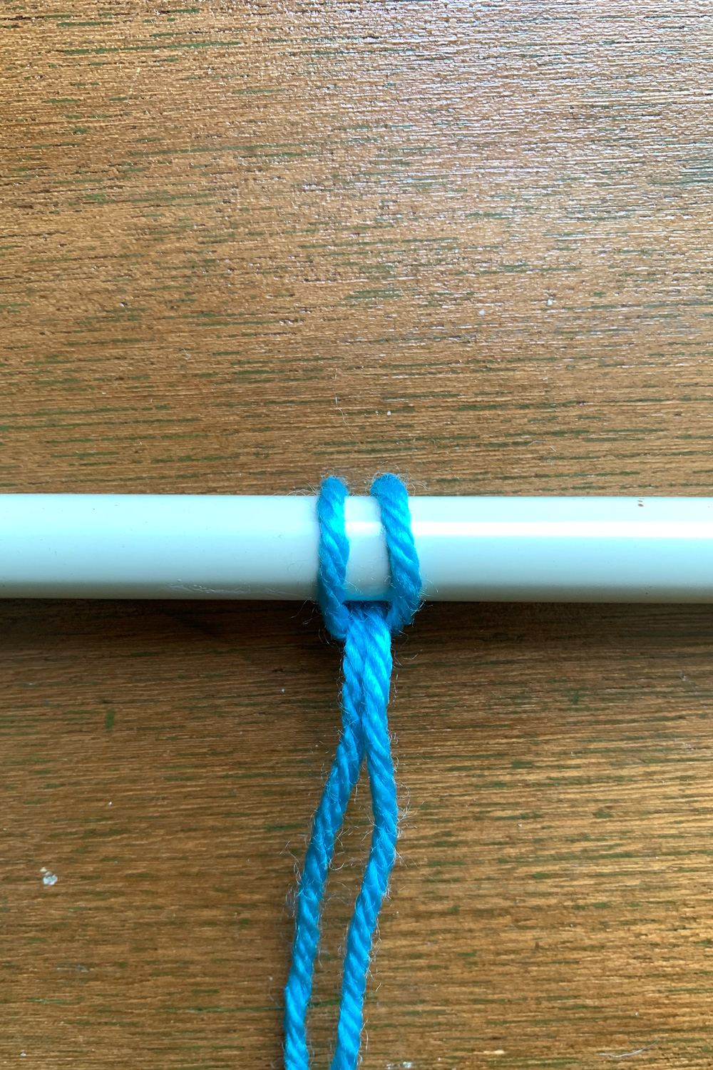 A tightened hitch knot looped over a metal rod.