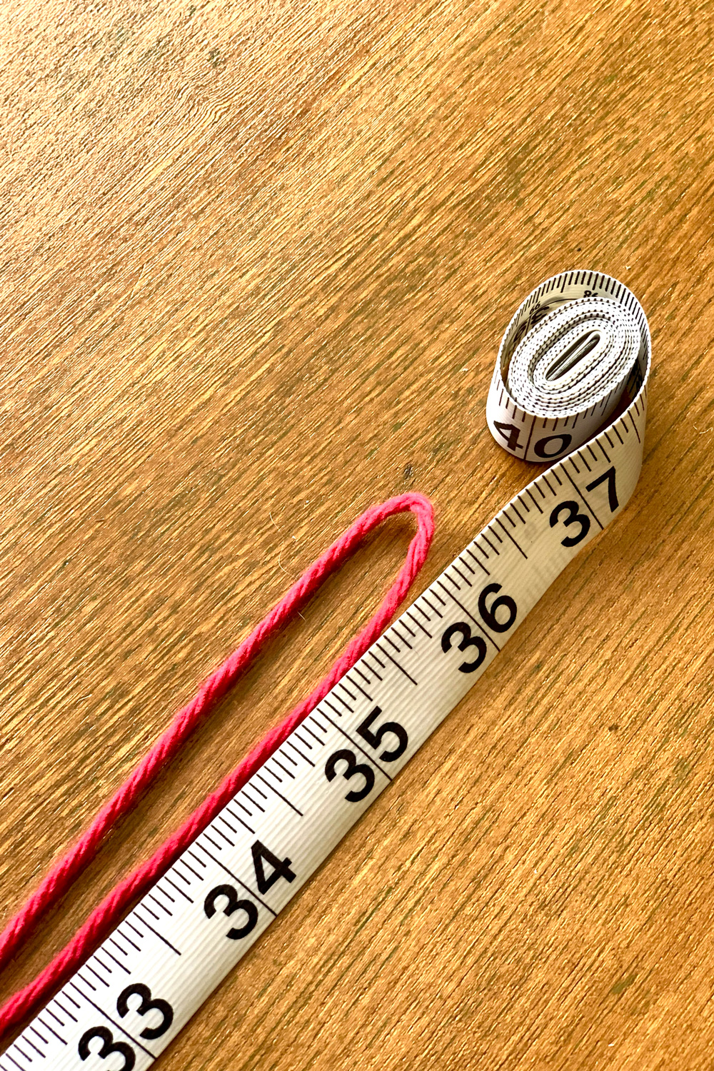 Red yarn measured to 36 inches on a tape measure and folded in half.