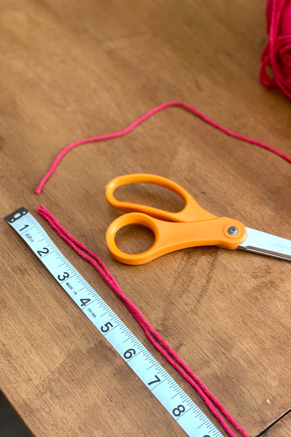 Red yarn beside a fabric tape measure.