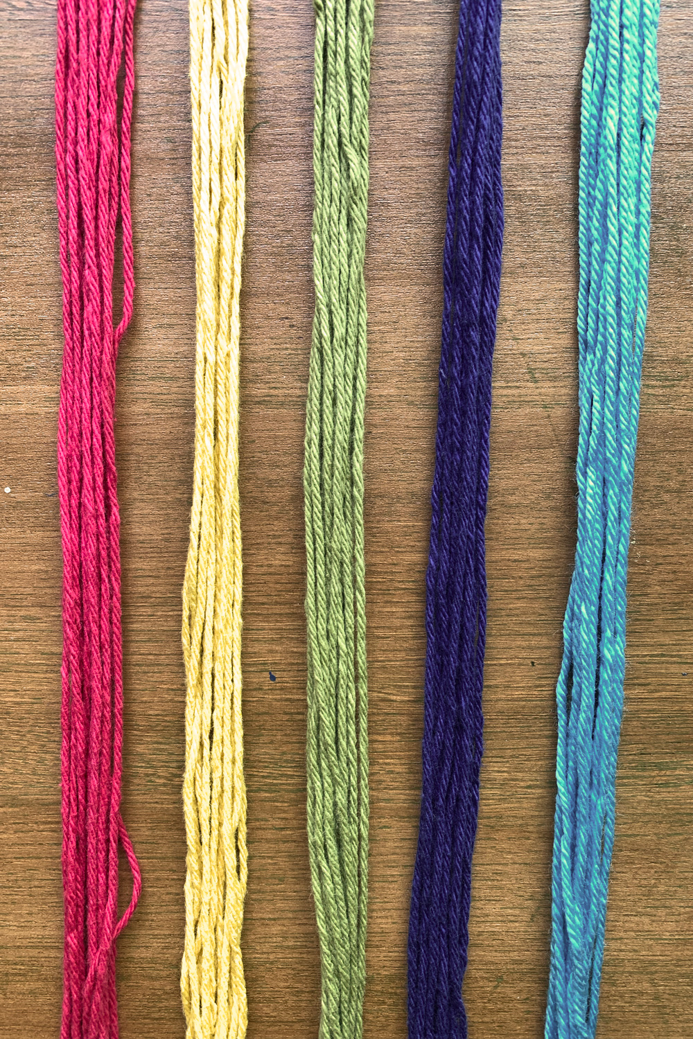 Bundles of red, yellow, lime green, navy, and teal yarn.