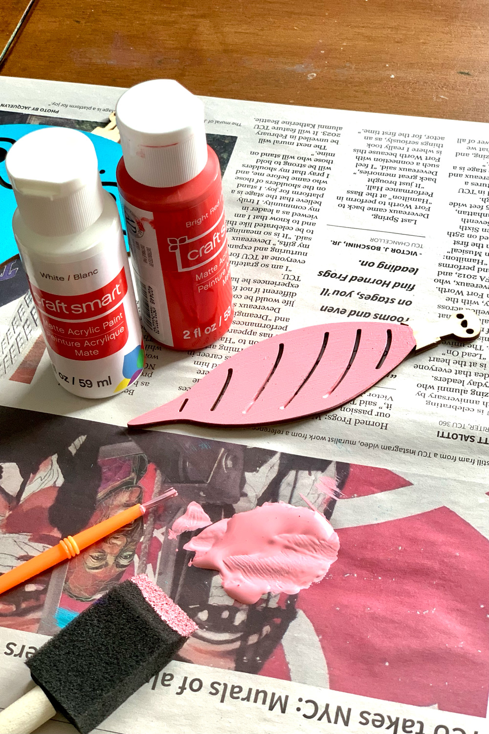 A wood ornament painted pink by mixing red and white paint.